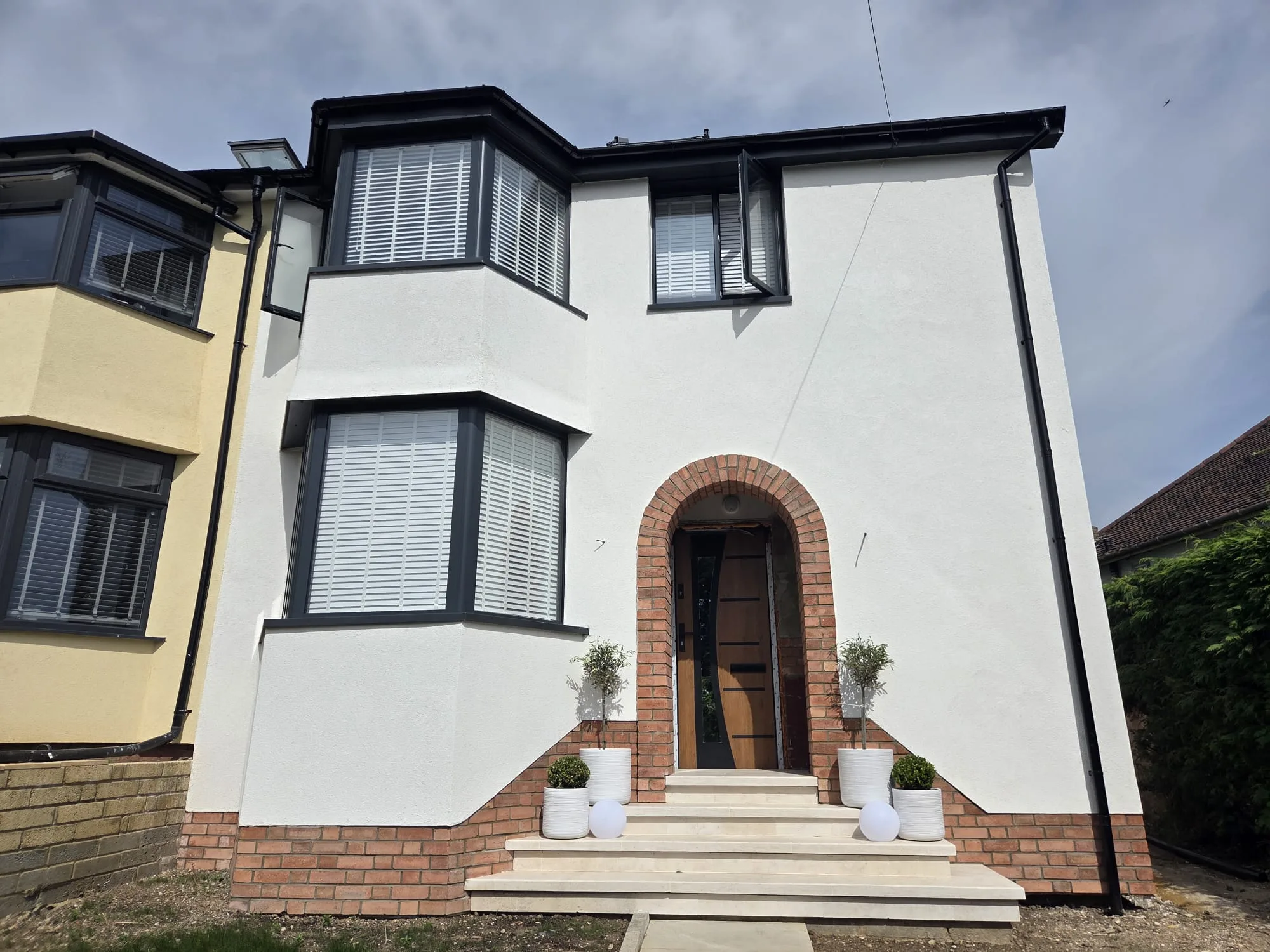 Front view of a modern home showcasing a recent refurbishment with a decorative entrance and clean lines