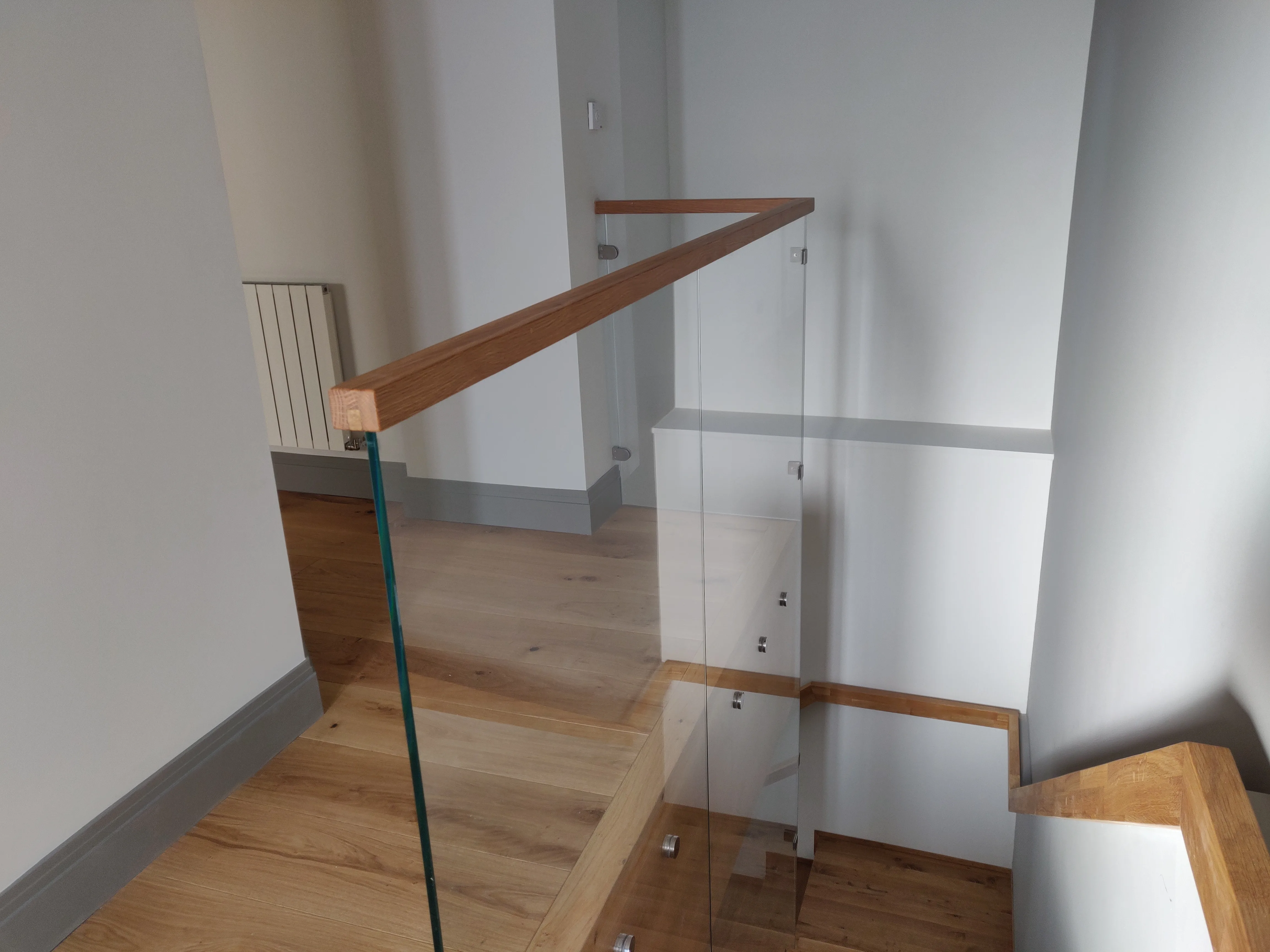 Modern wooden stairs with glass railings in a bright interior space