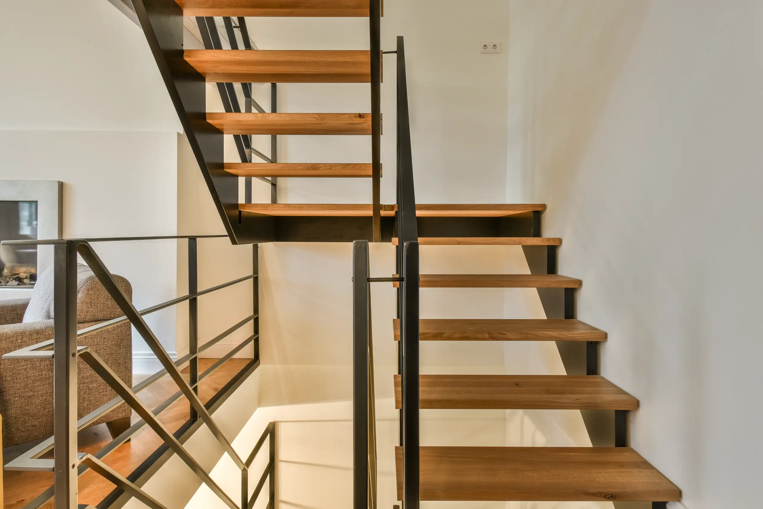 Modern floating stairs with wooden steps and metal railings in a well-lit interior