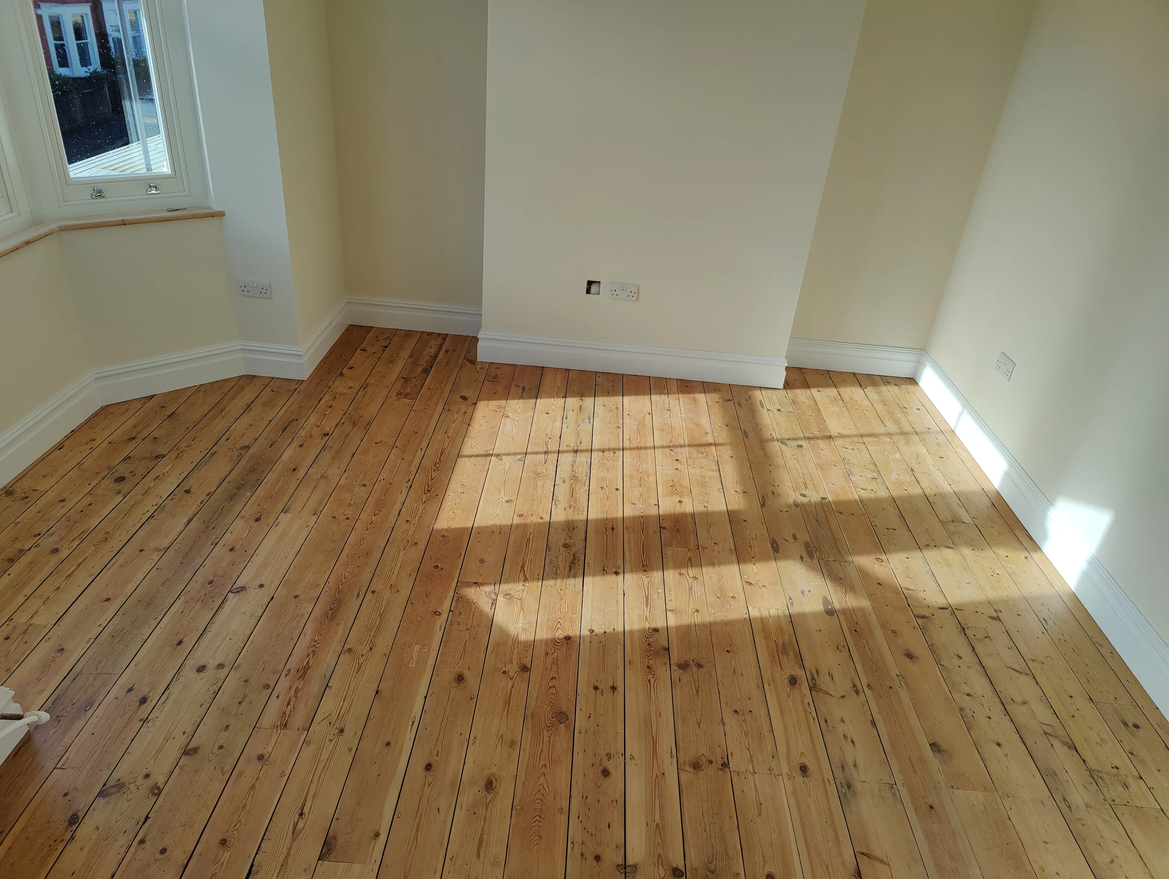 Newly installed wood flooring in a sunlit room showcasing natural light effects