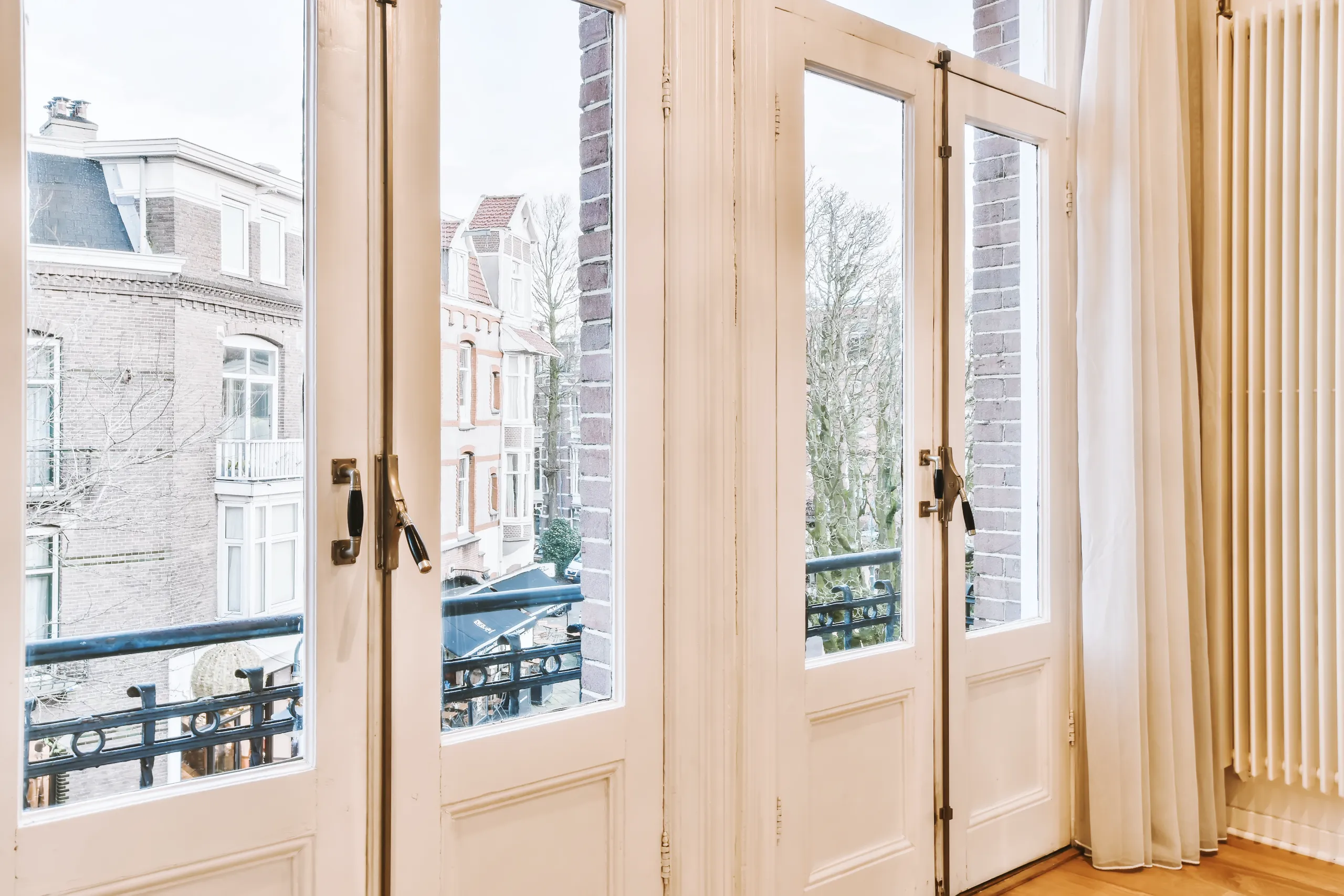White French doors opening to a balcony with a view of a street outside