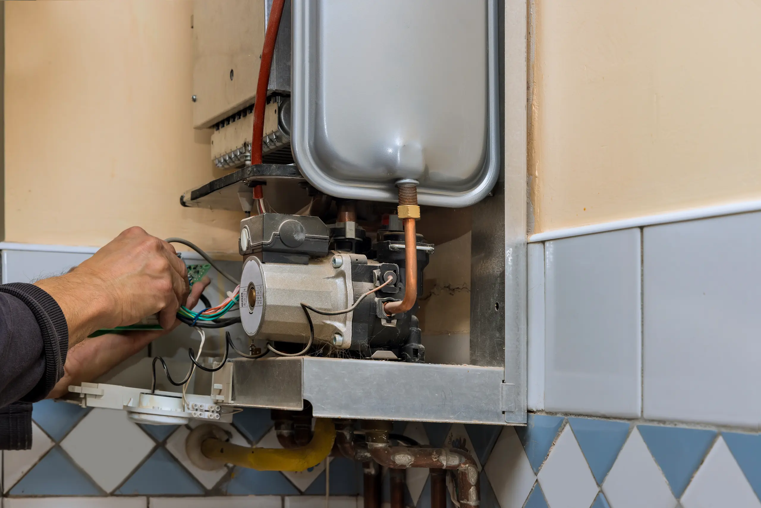 Installation of a gas boiler with visible piping and electrical connections