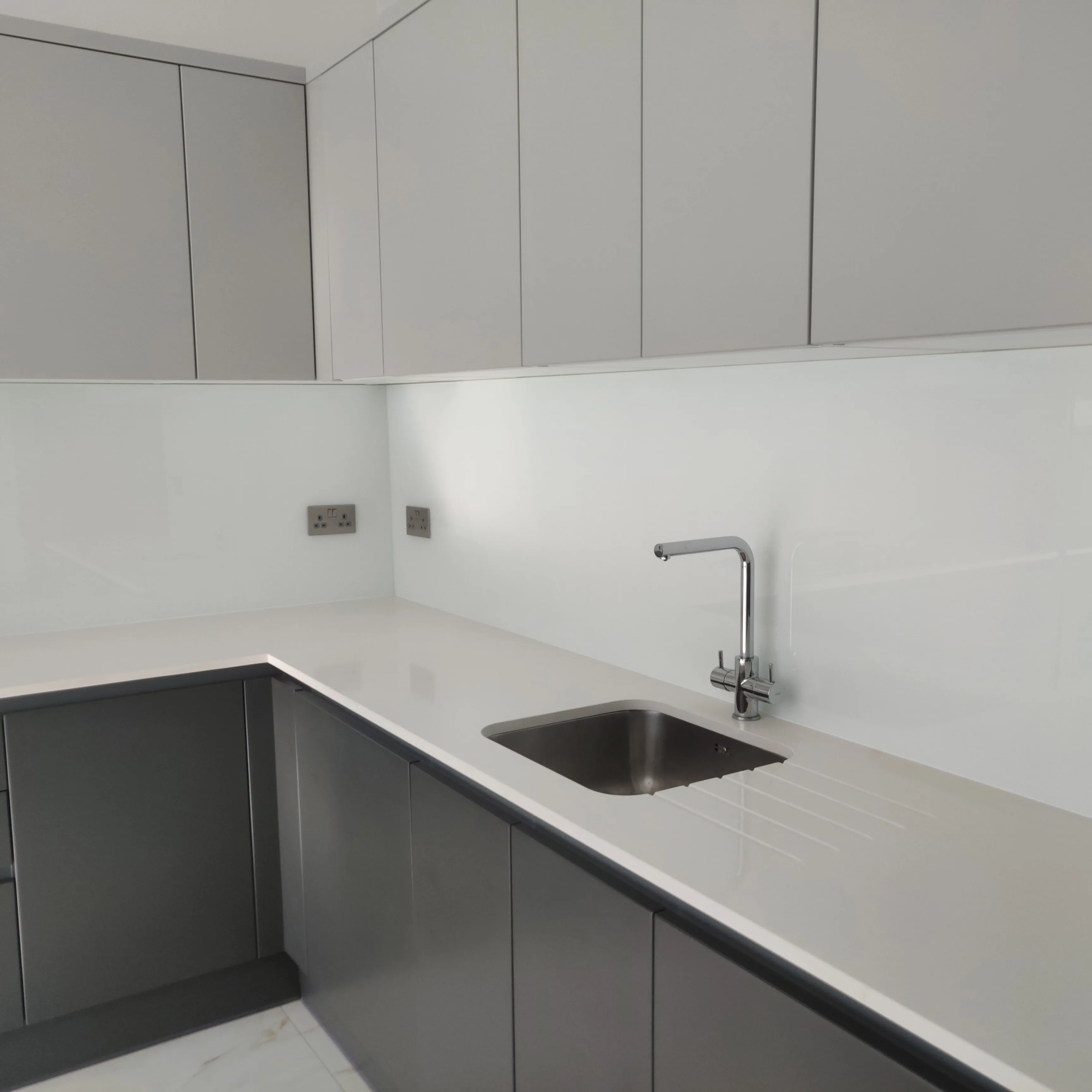 Modern kitchen refurbishment with sleek gray cabinets and a polished stone worktop