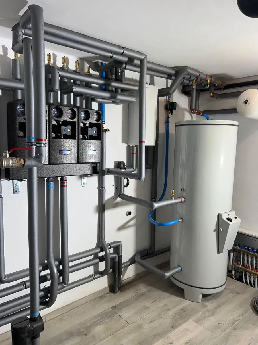 Plumbing installation with pipes and a hot water cylinder in a basement