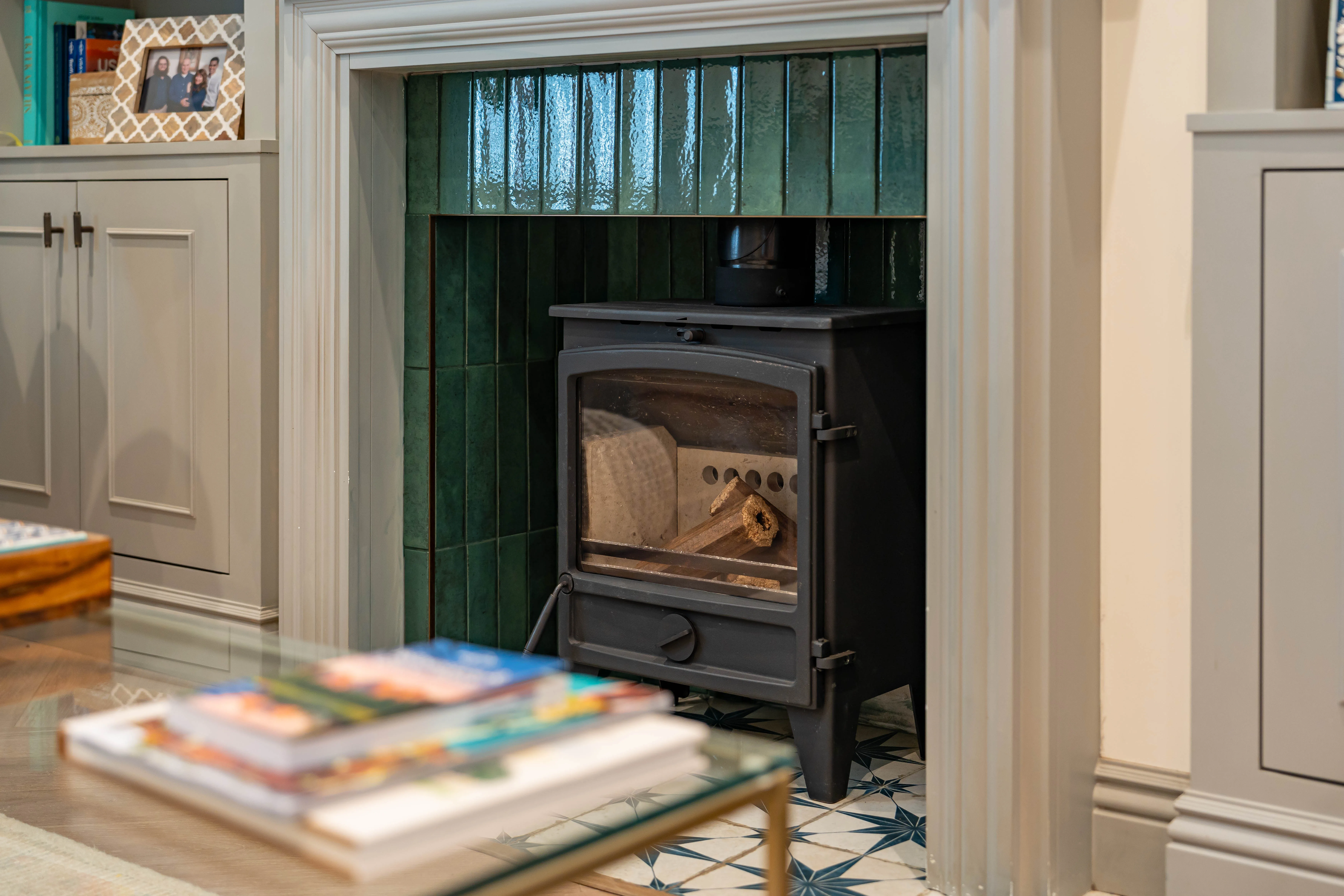 A stylish black stove with a green tiled backdrop, showcased in a cozy living space