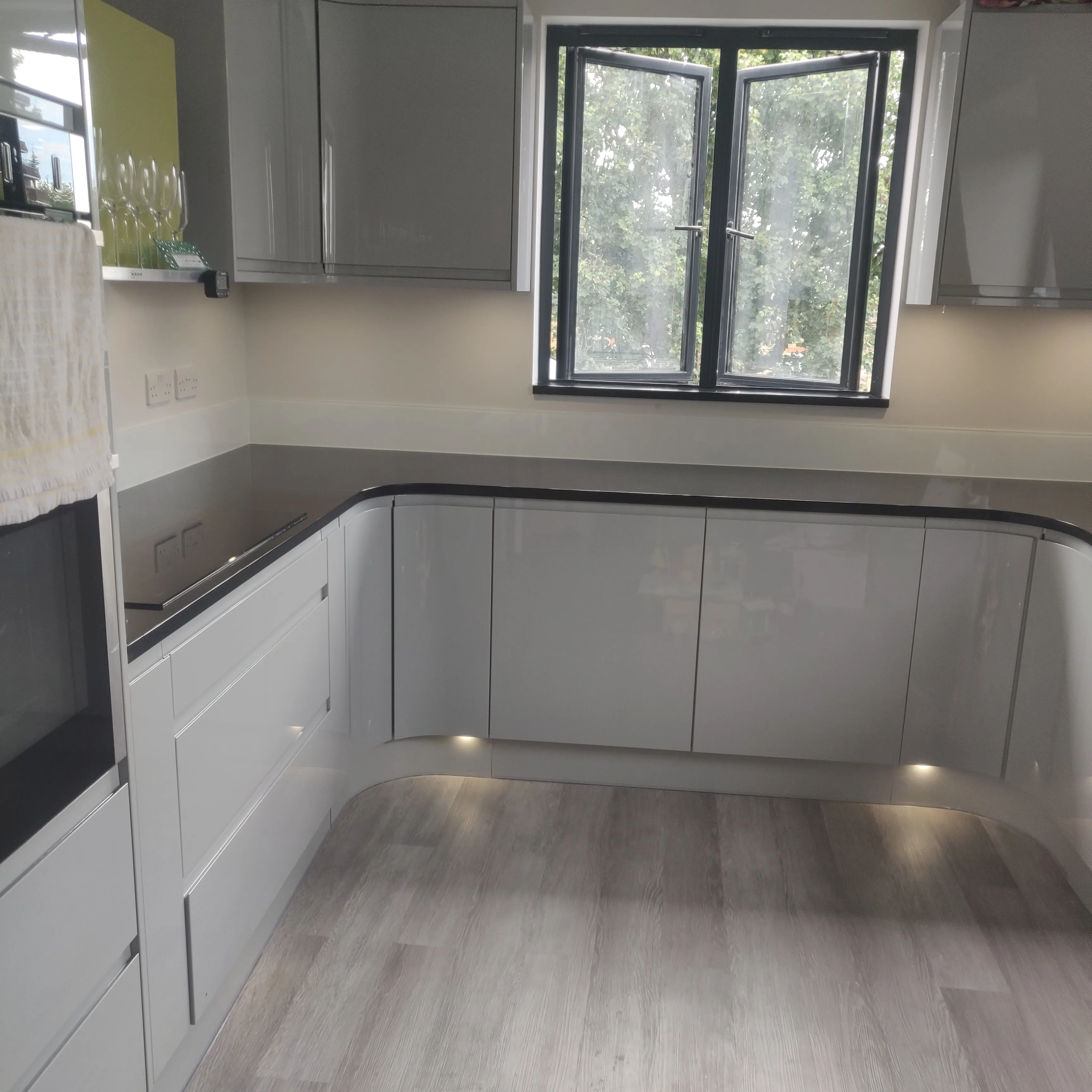 Modern kitchen refurbishment with grey gloss cabinets and sleek countertops