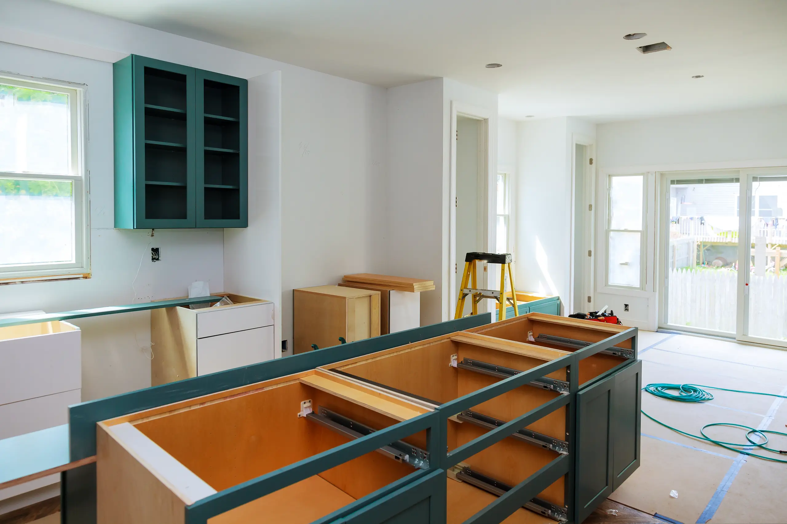 Kitchen installation with green cabinets and open drawers in a bright, unfinished space