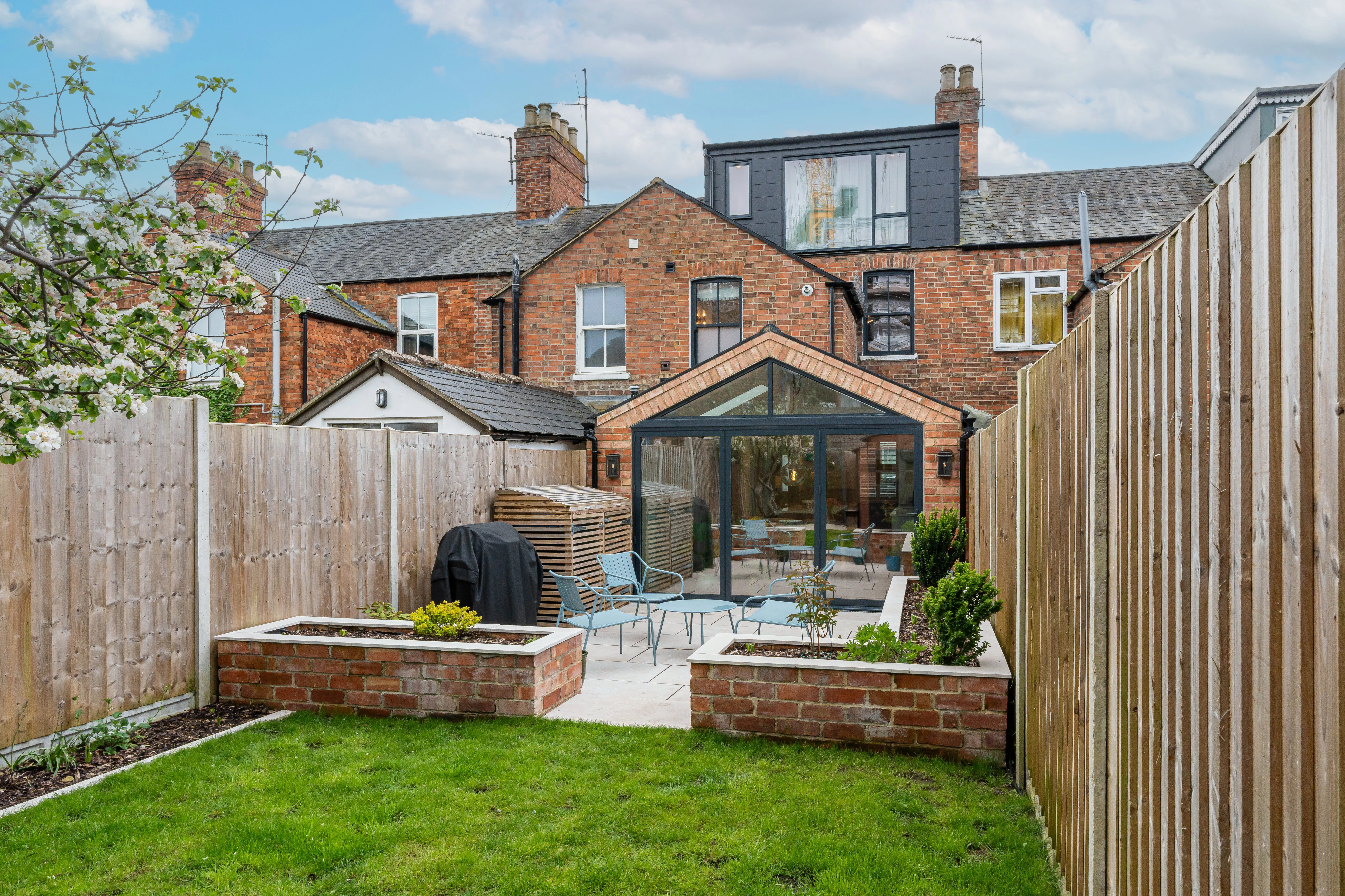 Backyard with a glass extension, featuring a patio and garden area