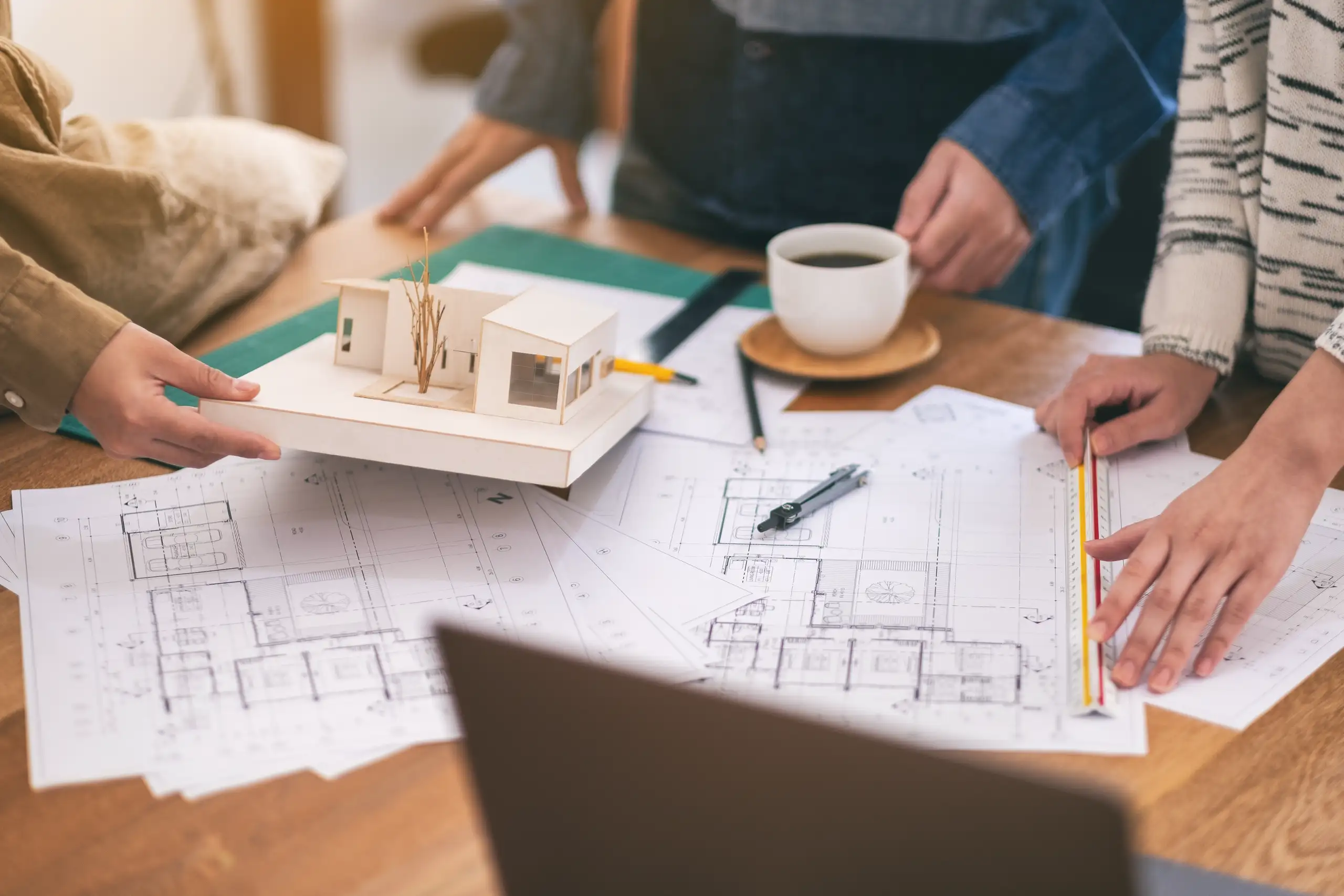 Team discussing home refurbishment plans with architectural models and blueprints
