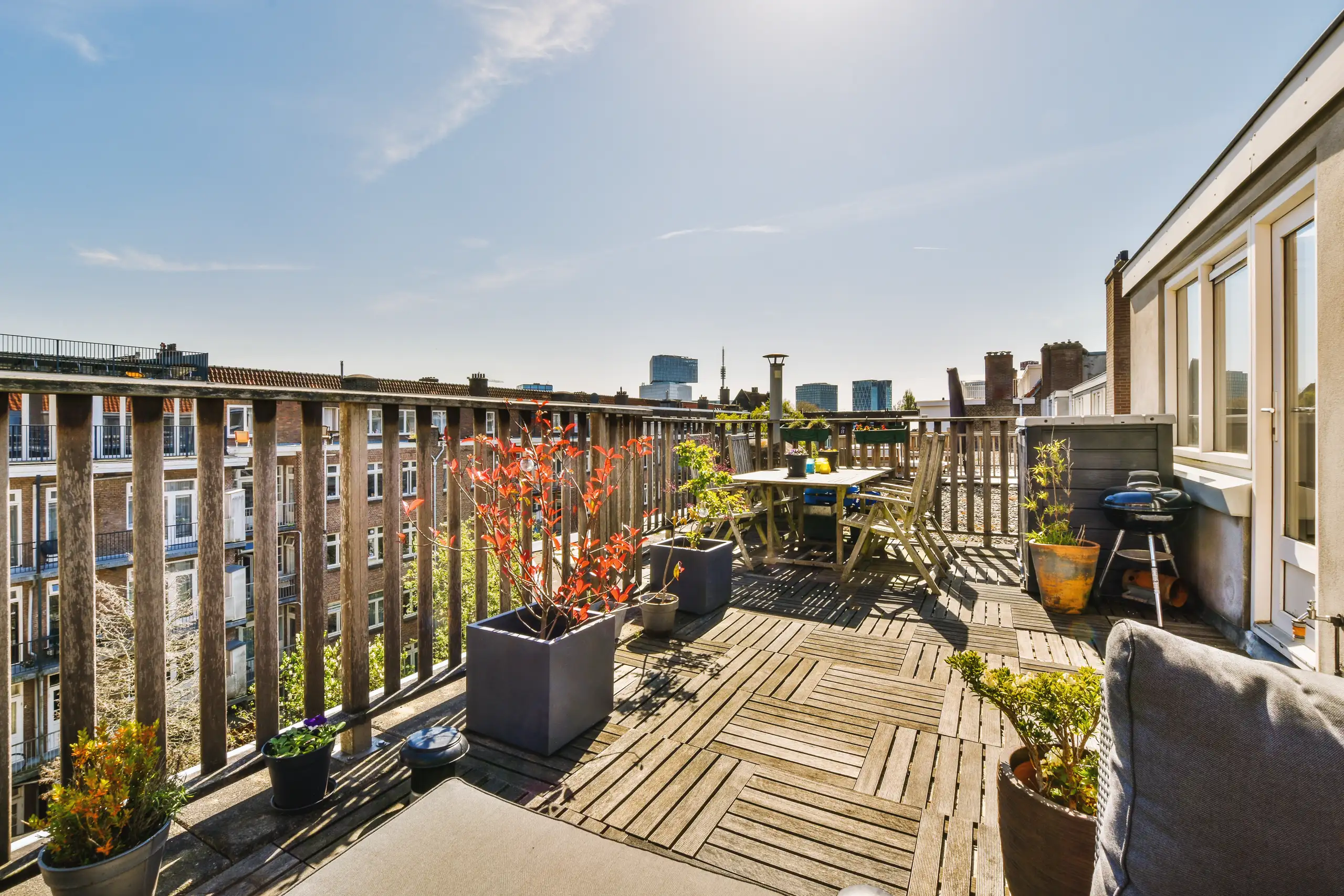 Rooftop terrace with wooden decking, potted plants, and city skyline views
