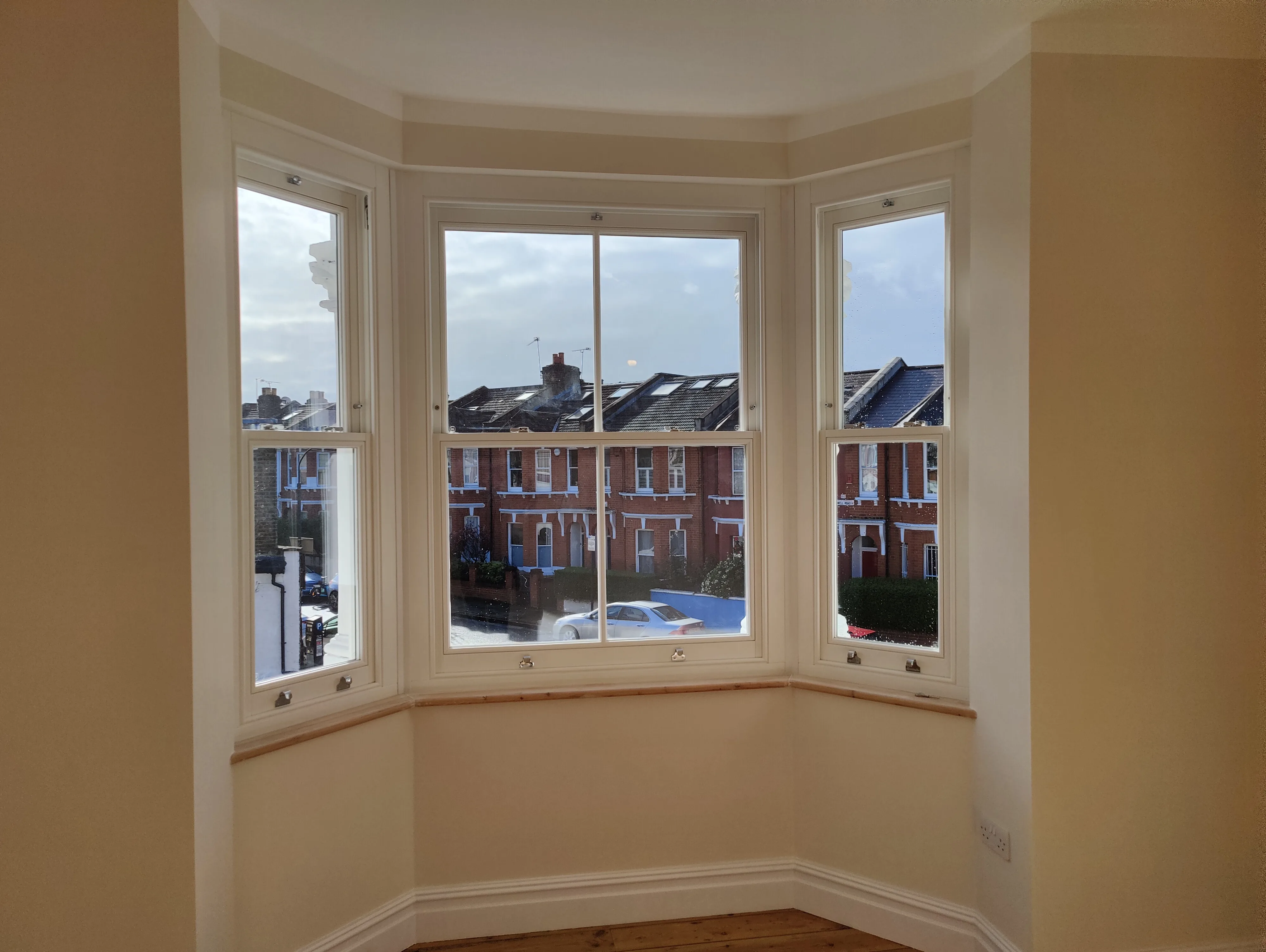 Bright interior showcasing newly installed sash windows with a view of the street