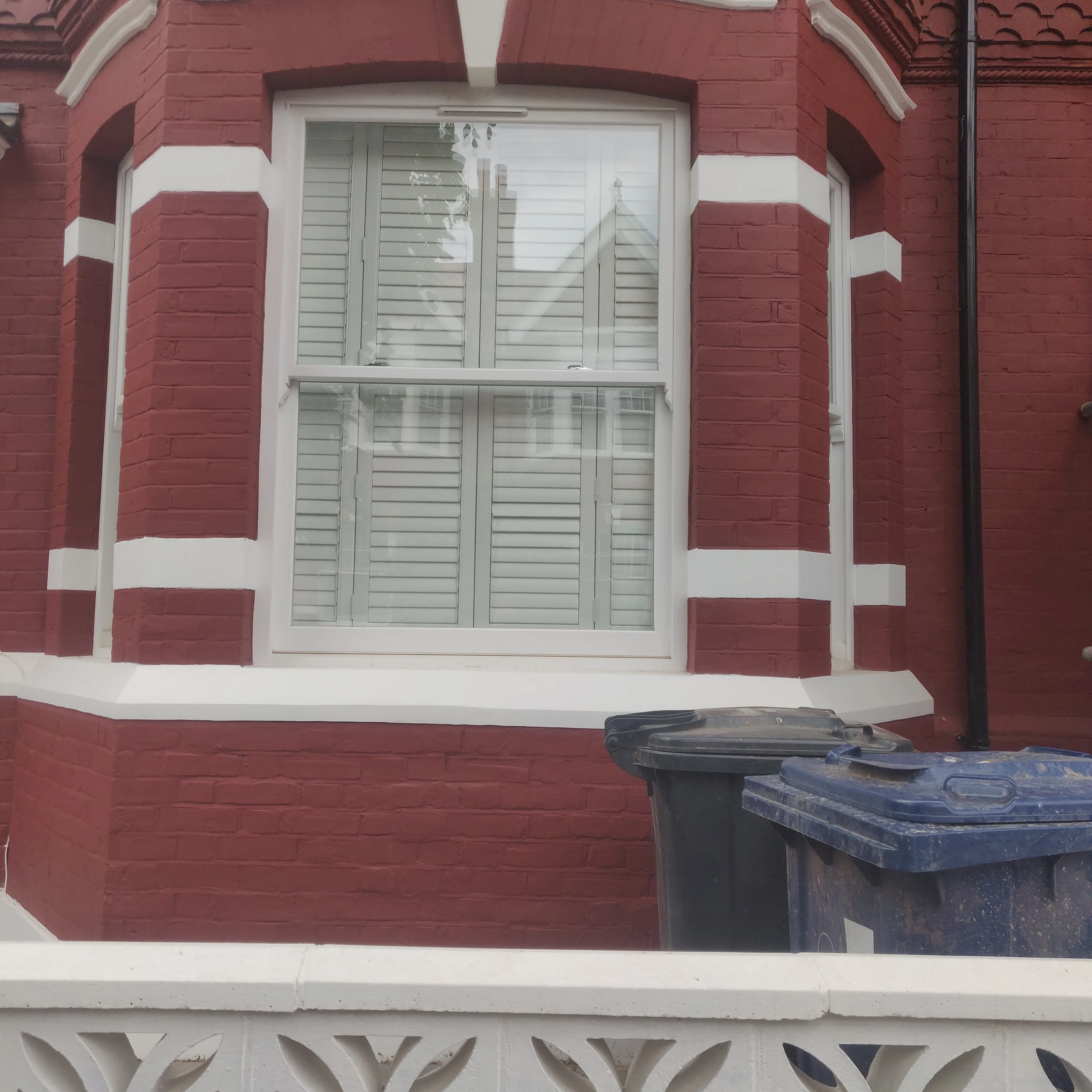 Close-up of a red brick window with white accents and shutters, showcasing window installation services