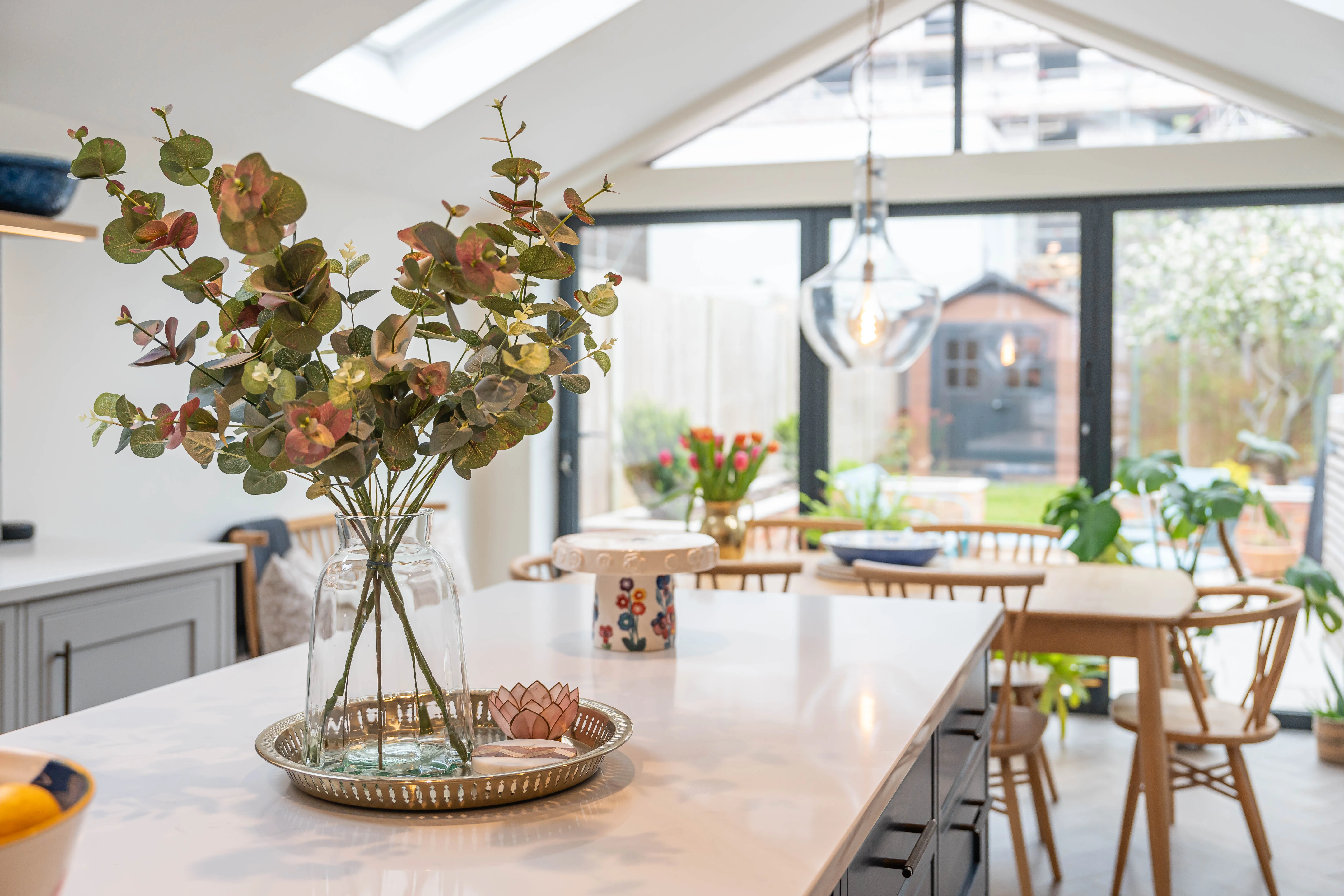 Modern kitchen with a central island, plants, and a large window letting in natural light