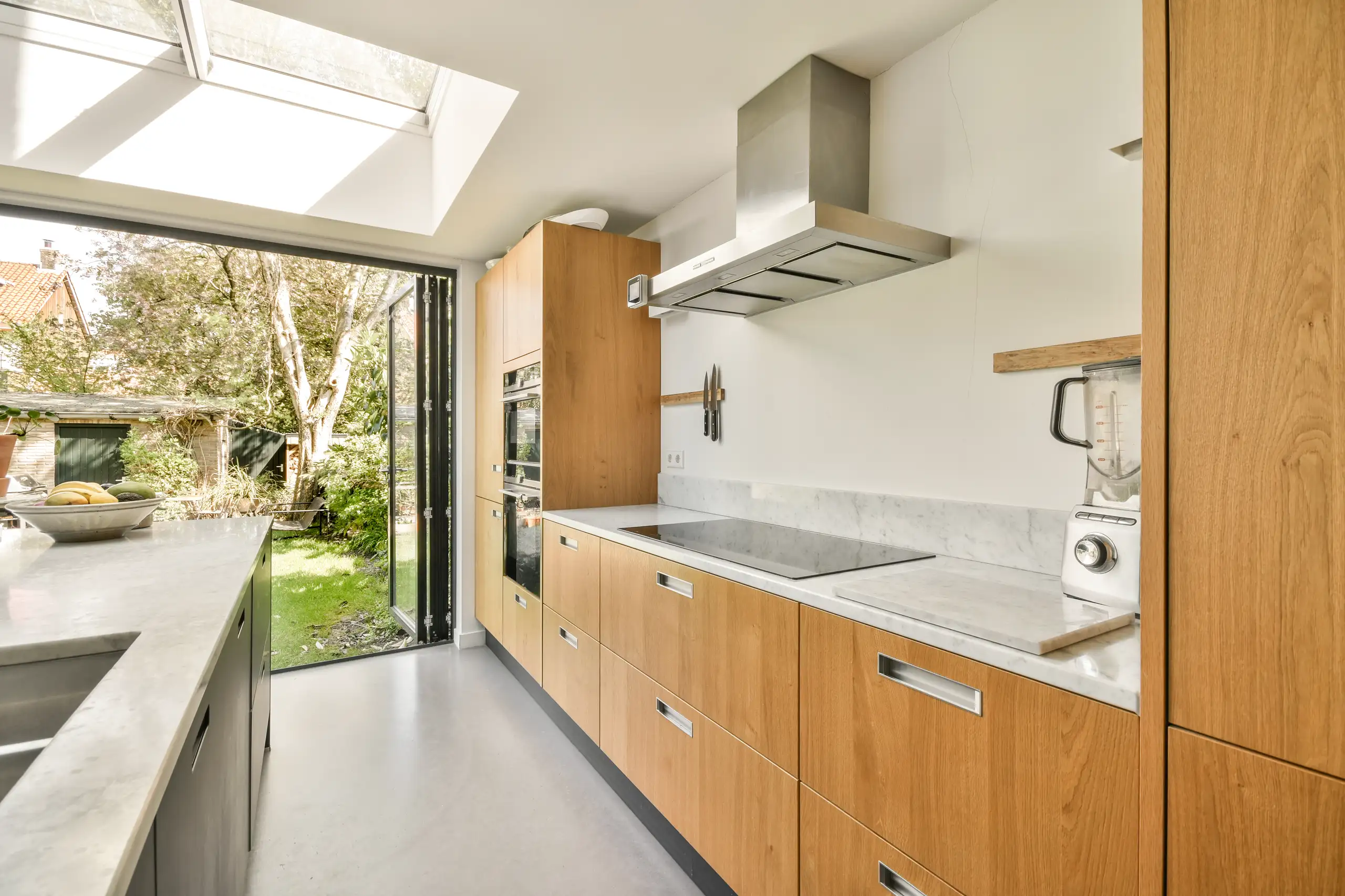 Modern kitchen refurbishment featuring wooden cabinets, a marble countertop, and a skylight