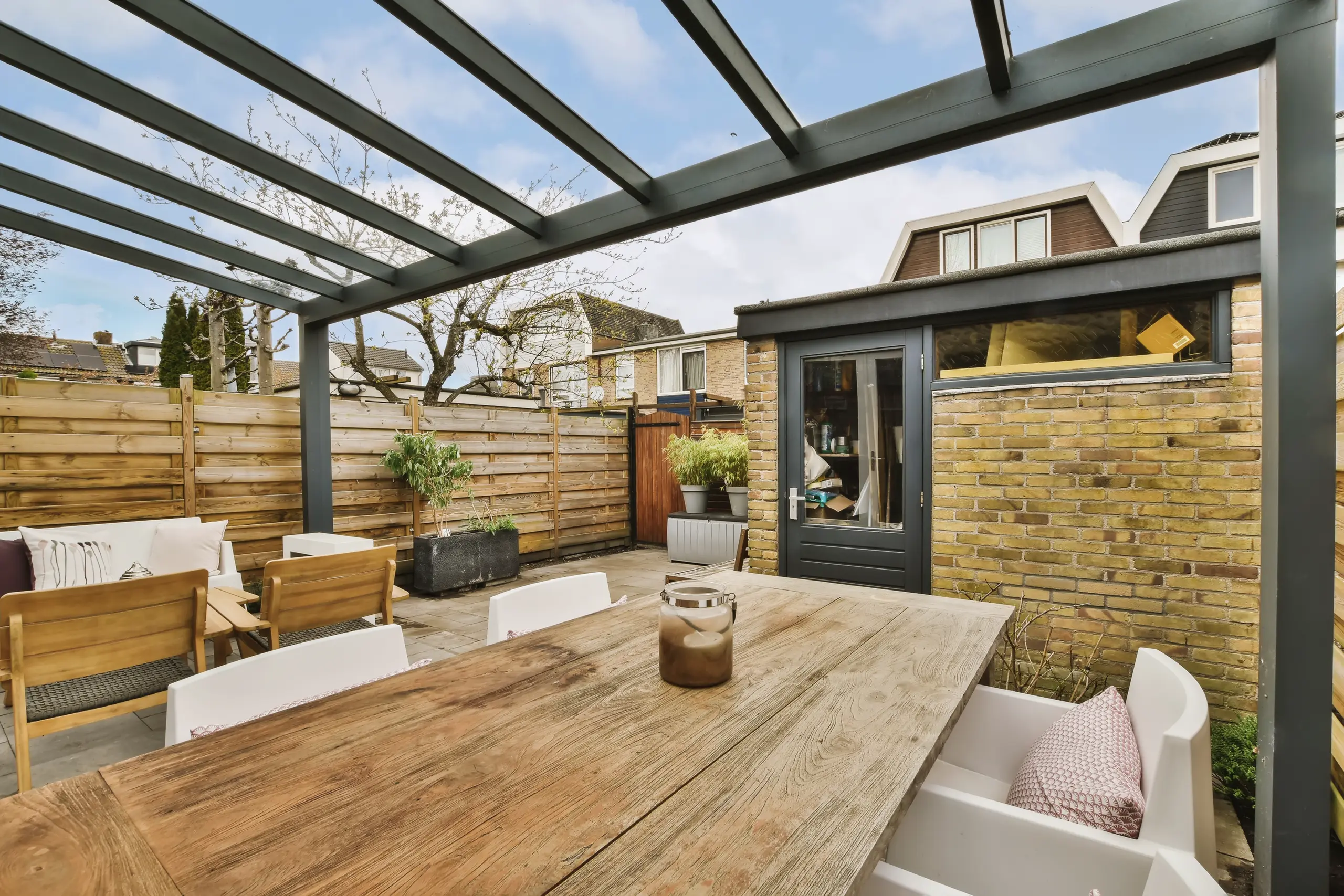 Outdoor space featuring a glass roof, wooden table, and a modern garden layout