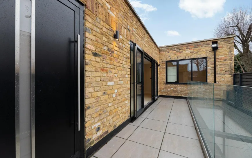Modern roof terrace with stone floor and glass railing, showcasing a stylish outdoor living space