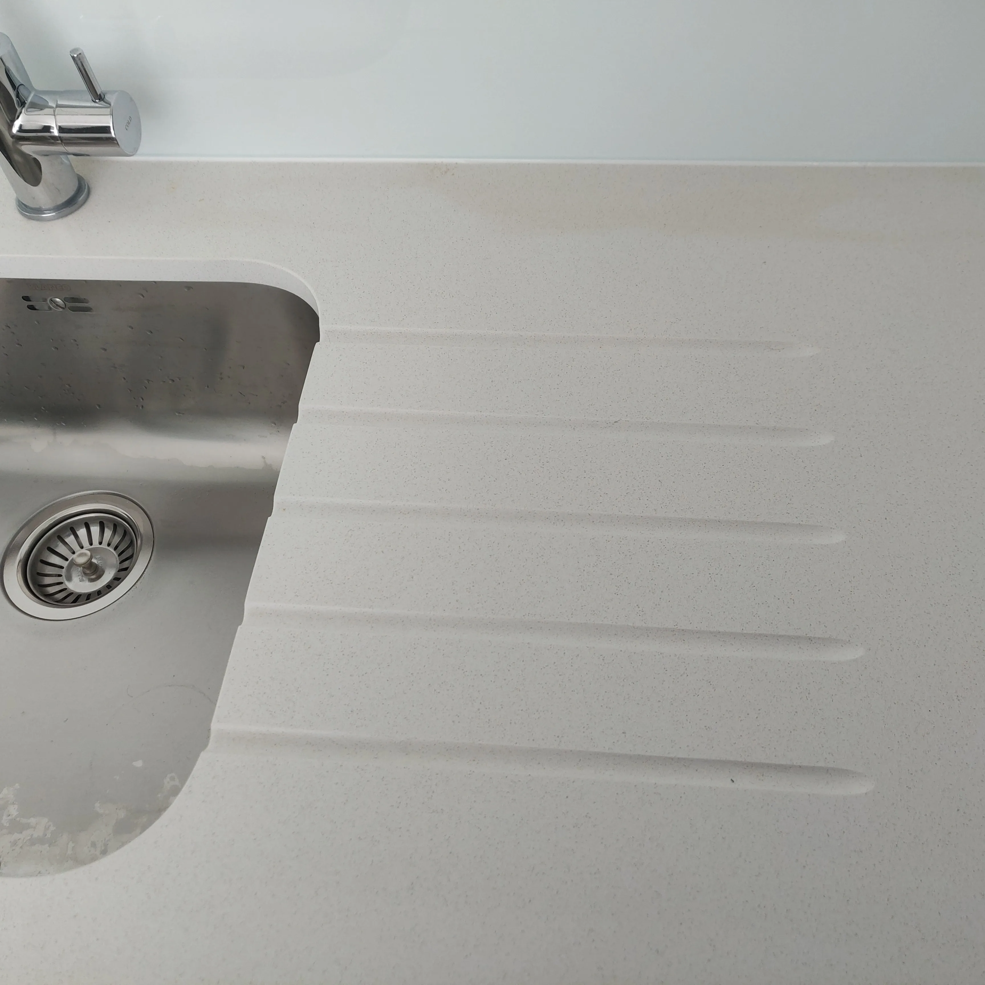 Close-up of a stone worktop with a sink and drainage grooves