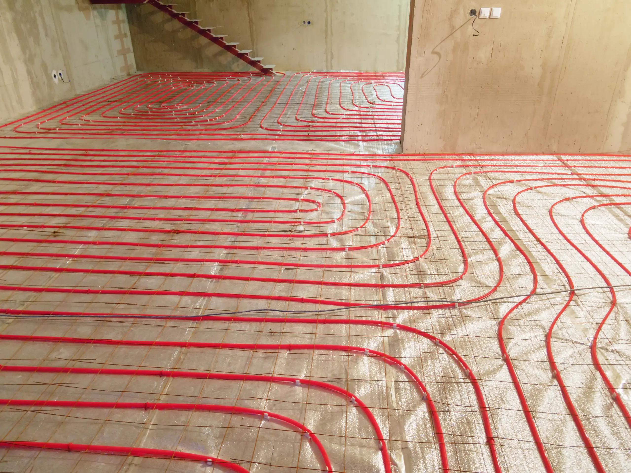 Underfloor heating installation with red piping laid on the floor