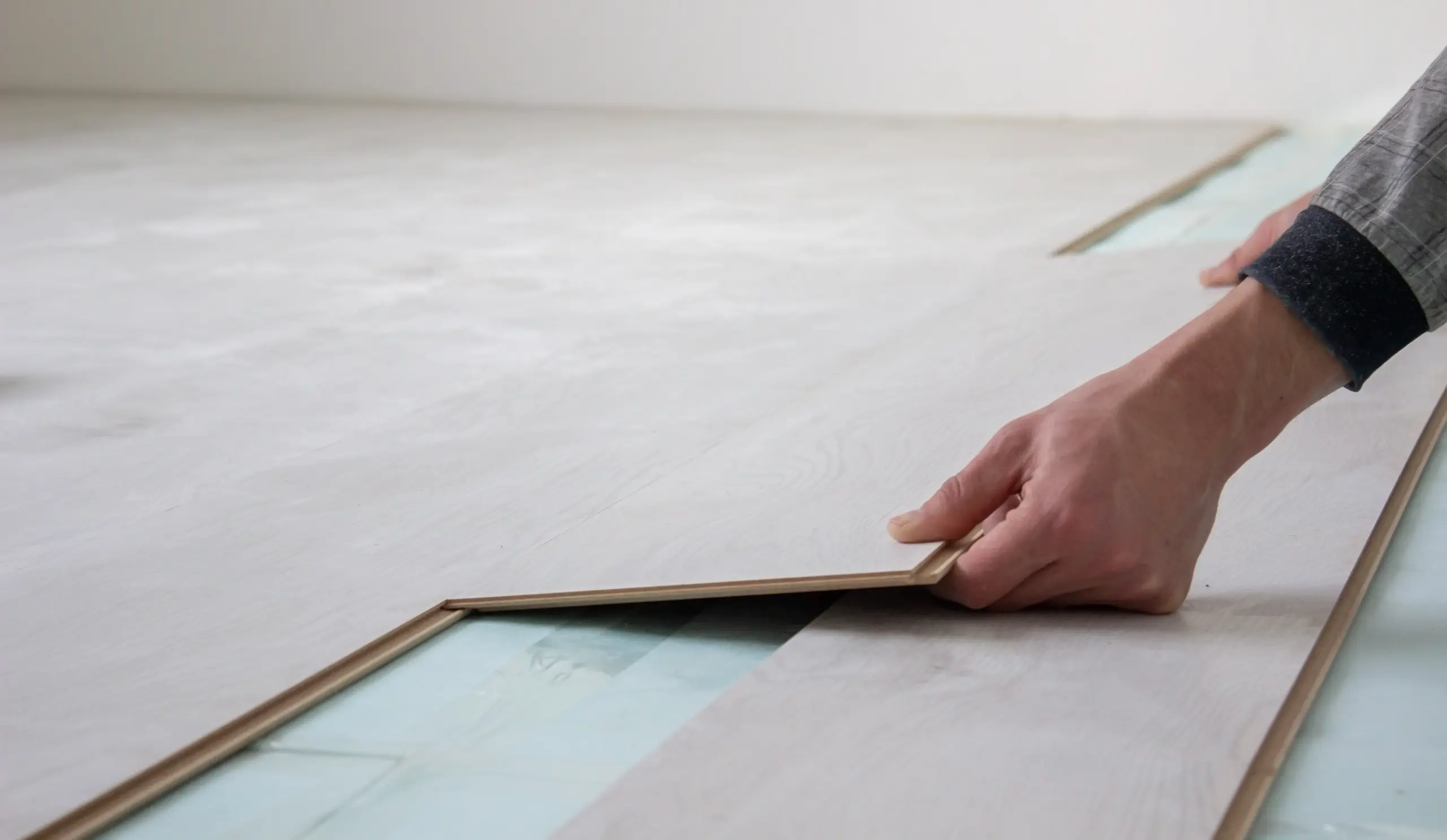 A person installing wood flooring in a residential space, showcasing a close-up of the flooring process